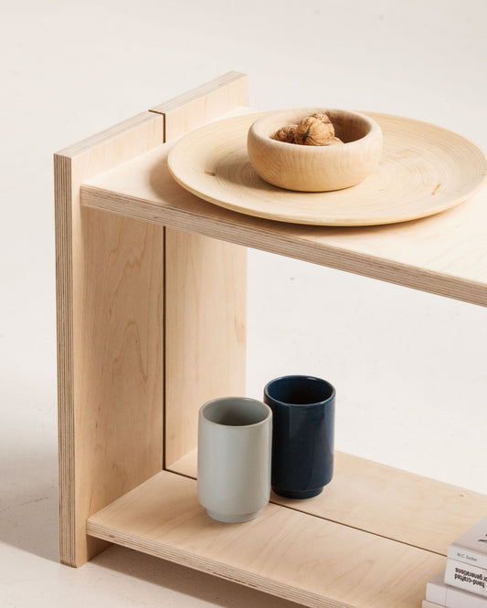 Wooden stool with ceramic bowls and cups on a light background