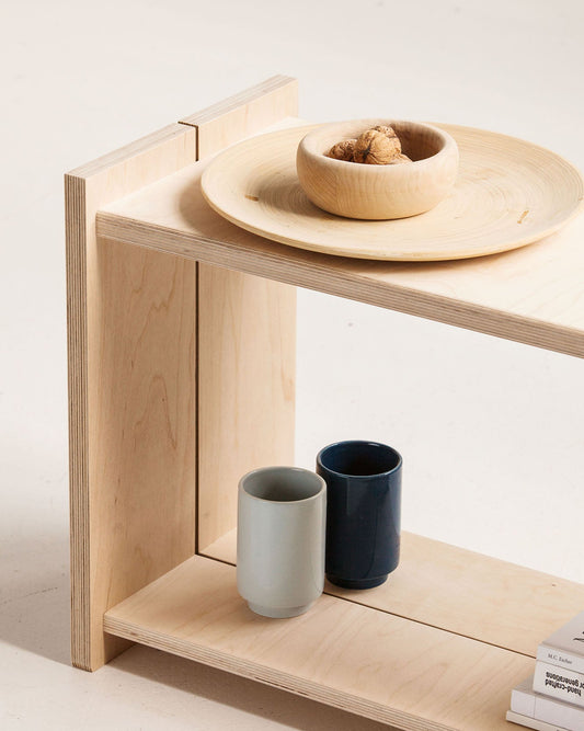 Wooden shelf with ceramic bowls and cups on a light background