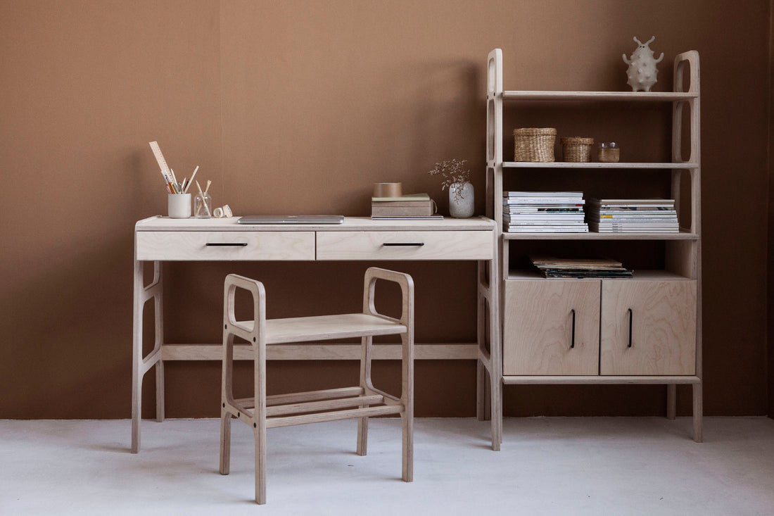 Birch plywood bench stool at a mid-century desk beside a bookcase, in a warm minimalist interior