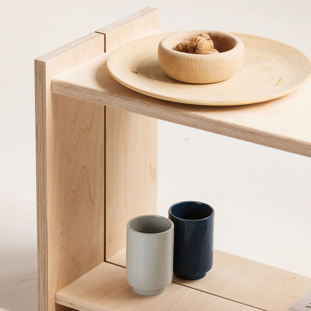 Wooden stool with ceramic bowls and cups on a light background