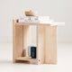 Wooden stool with a white top holding books and a bowl on a light gray background