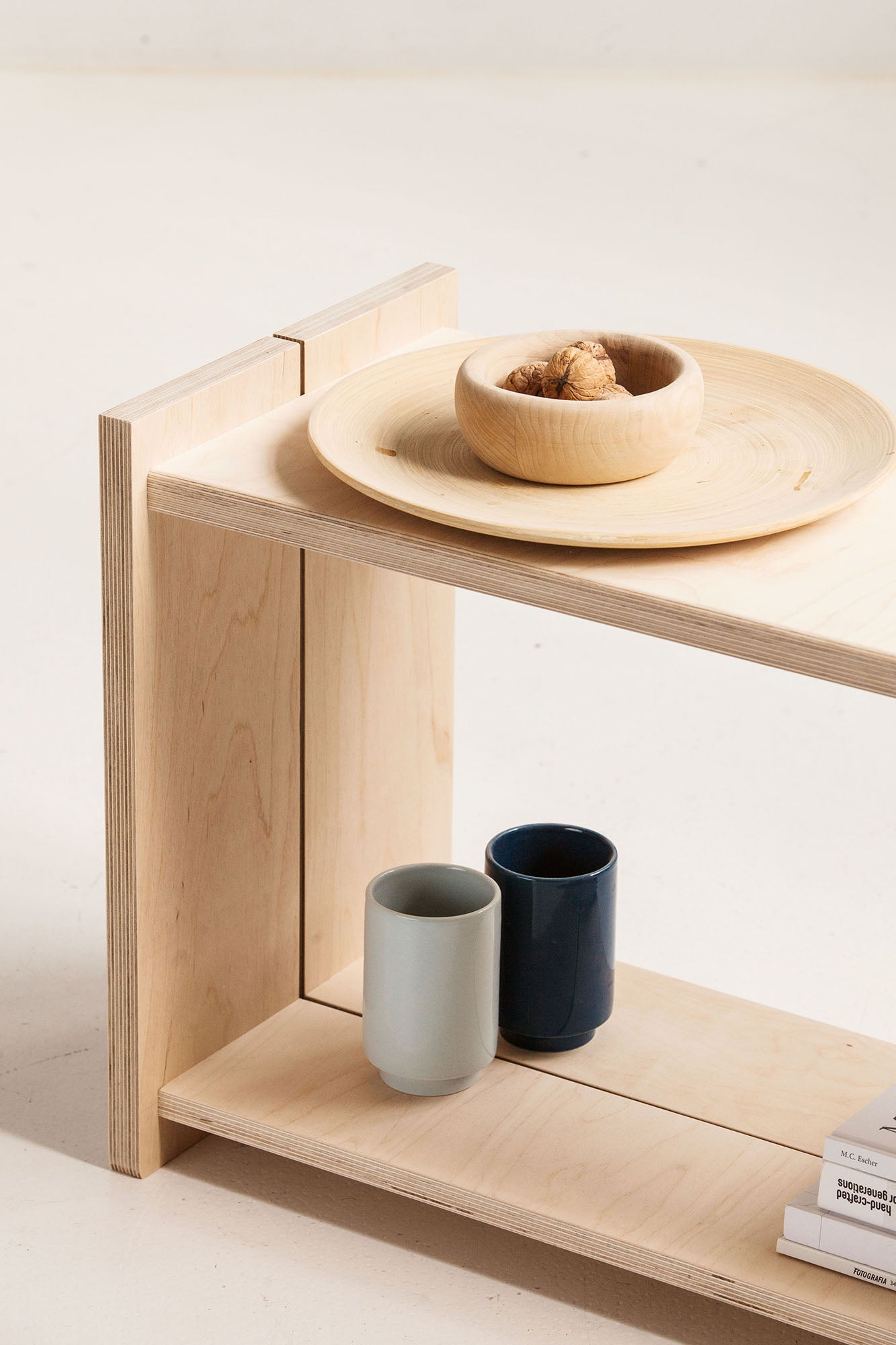 Wooden shelf with ceramic bowls and cups on a light background